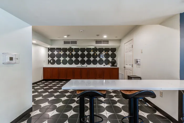 Chic modern kitchen with bold geometric tile floor, elegant wooden cabinets, and stylish bar seating.