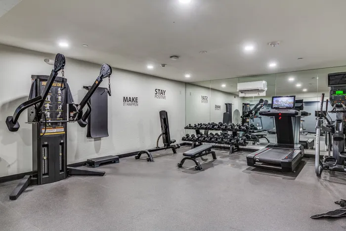 Modern apartment gym featuring state-of-the-art fitness equipment, mirrored walls, and motivational decor.