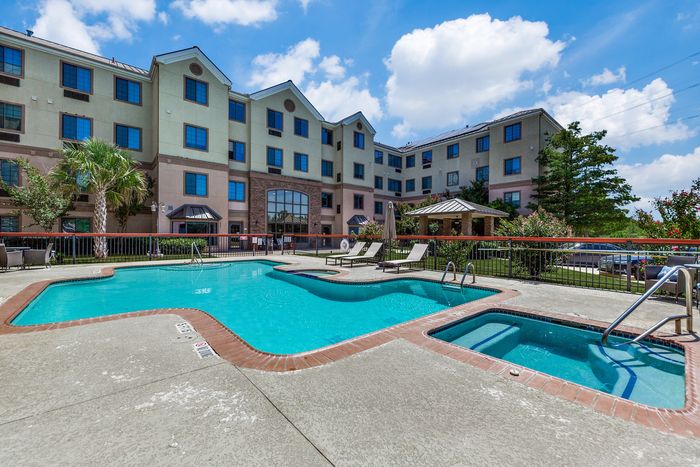 Inviting apartment complex with a sparkling outdoor pool and lush landscaping, perfect for relaxation and leisure.