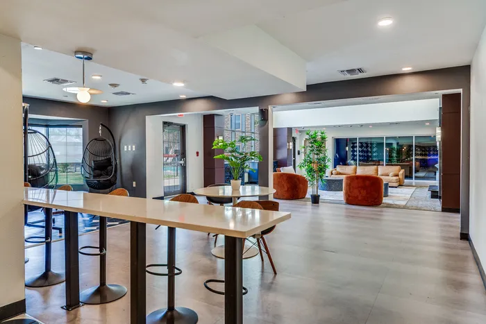 Modern bar area inside Onyx at Oslo with high top bar tables, bar stools, hanging chairs in the corner, and bright natural light coming through large windows.