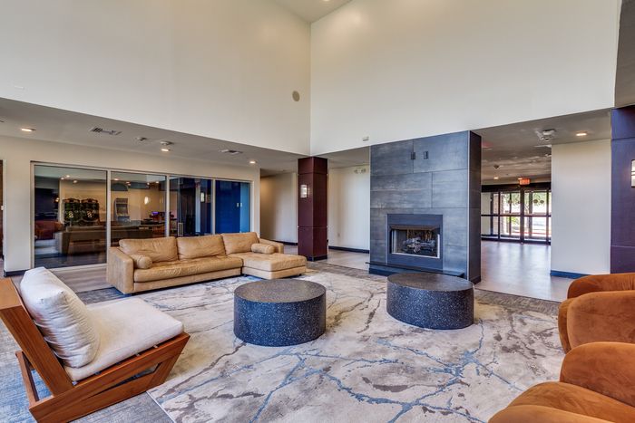 Lobby area featuring a leather sofa, lounge chair, round tables, and a built-in fireplace.