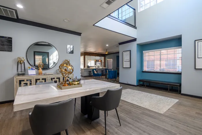 Spacious room with a large table, modern chairs, decorative accents, and open views into an adjacent seating area.