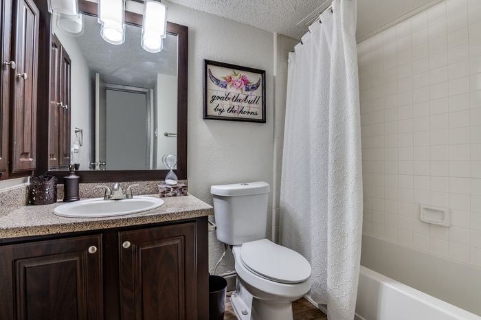 A clean and practical bathroom layout featuring warm cabinetry, a spacious vanity area, and a simple shower&ndash;tub combination.