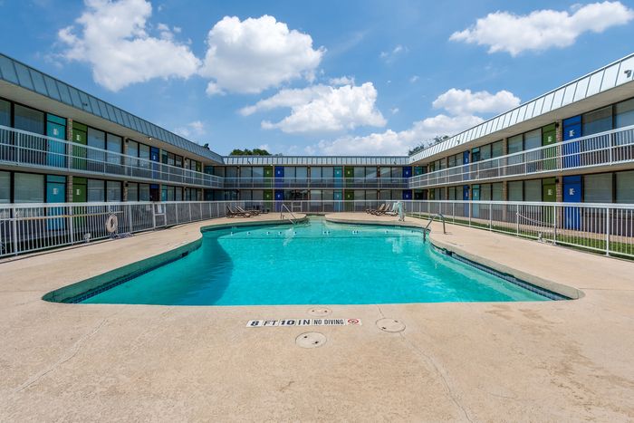 Inviting apartment complex showcasing a sparkling outdoor pool surrounded by colorful doors and sleek balconies, perfect for relaxation and leisure.