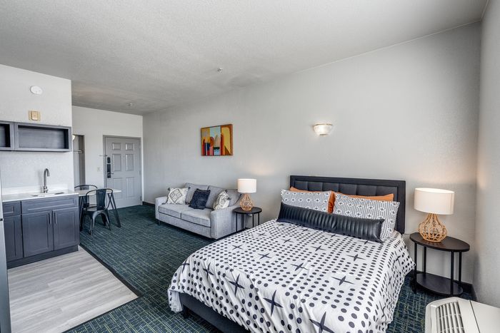 Cozy studio at Gruene Pointe in New Braunfels, TX with a bed, sofa, and compact kitchenette