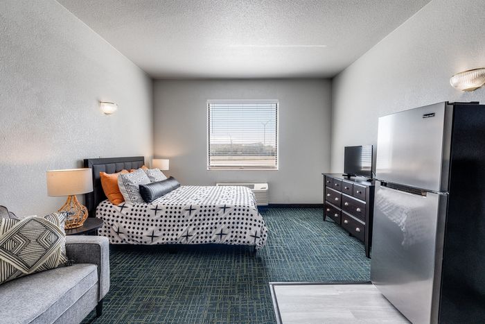 Furnished studio at Gruene Pointe in New Braunfels, TX with a bed, sofa, and stainless fridge