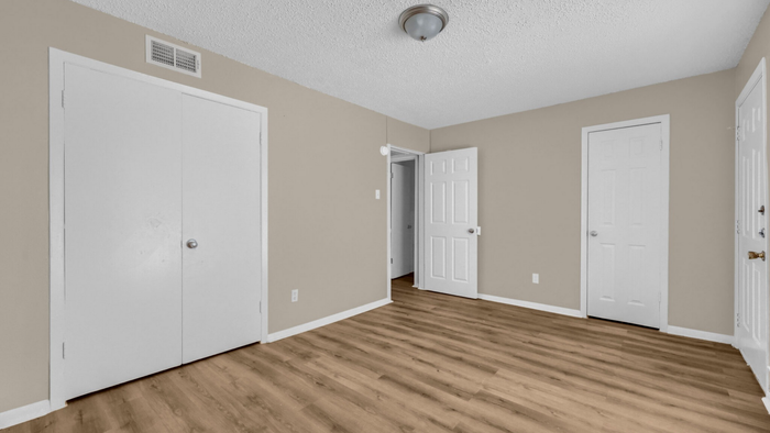 Inviting room with elegant wood flooring, neutral walls, and ample closet space, perfect for a cozy bedroom setup.