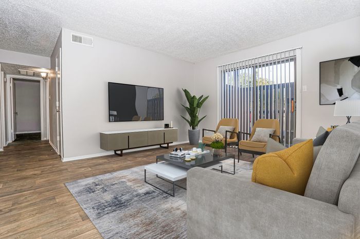 Living room with a wall-mounted TV and window in a Dakota Apartments unit