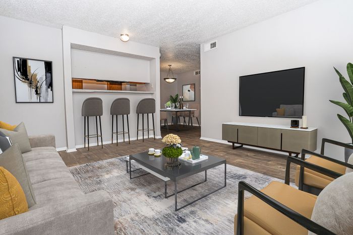 Living room with a TV and bar seating in a Dakota Apartments unit
