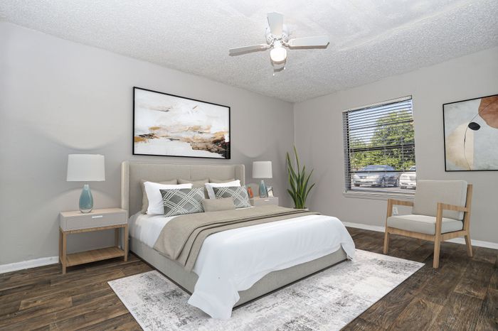 Furnished bedroom with a bed and an accent chair by the window in a Dakota Apartments unit