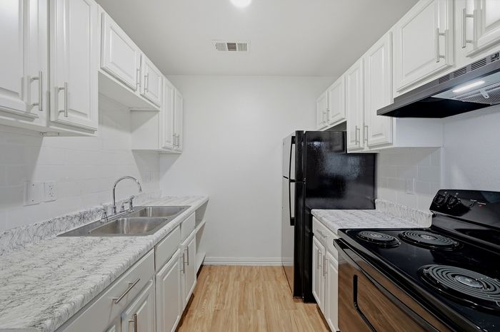 Contemporary kitchen with sleek black appliances, elegant marble countertops, and white cabinetry for a modern touch.