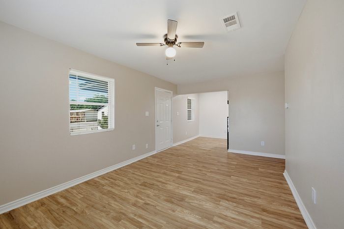 Bright and airy living space with beautiful hardwood floors, ceiling fan, and abundant natural light from large window.