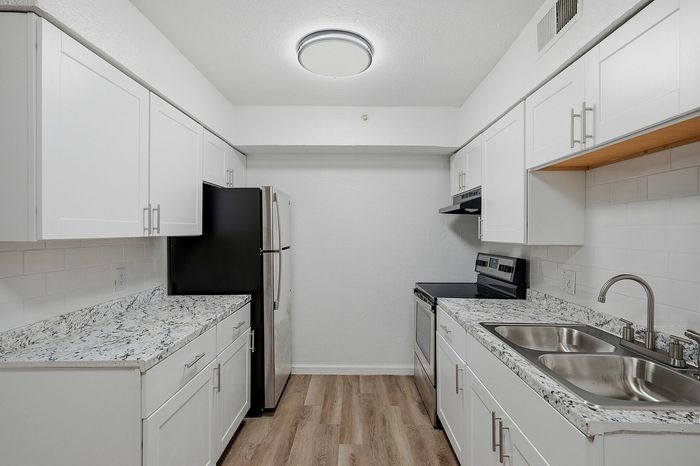 Modern kitchen with sleek granite countertops, stainless steel appliances, and elegant white cabinetry offering a bright and inviting space.