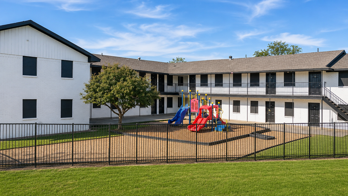 Inviting apartment complex with a vibrant playground and lush green surroundings, perfect for family living.