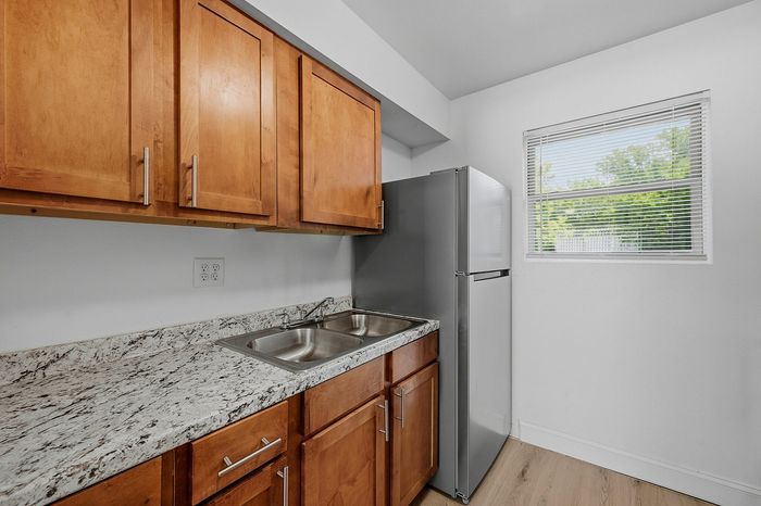 Kitchen with granite-look countertops, stainless sink, and wood cabinetry at The Crawford at Denison