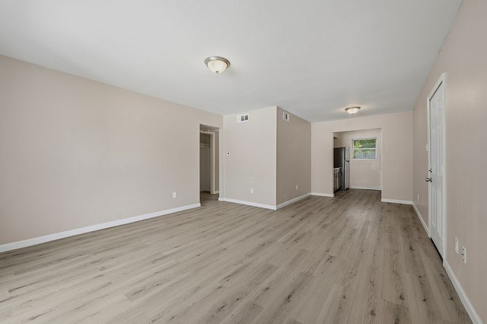 Living area with wood-style flooring open to the kitchen at The Crawford at Denison
