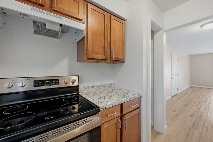 Kitchen with stainless steel range, wood cabinets, and stone-look countertops at The Crawford at Denison