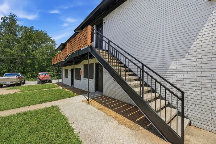 Two-story building entrance with metal stairs and a wood railing at The Crawford at Denison