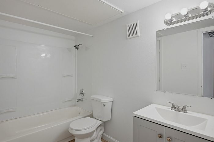 Bathroom with white fixtures, a bathtub, and a vanity at The Crawford at Denison