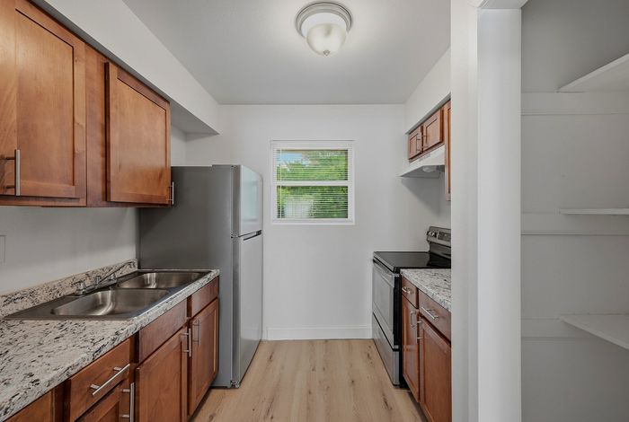 Kitchen with granite-look counters, stainless appliances, and wood cabinets at The Crawford at Denison