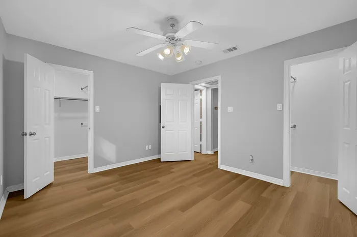 Bright and airy bedroom with elegant hardwood floors and dual walk-in closets.