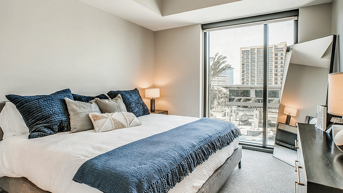 Staged sleeping area in a studio apartment at Oslo on 6th in Aurora, CO, with a made bed and a tall window