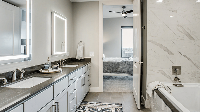 Apartment bathroom with a vanity, mirror and tile at Oslo on 6th in Aurora, CO