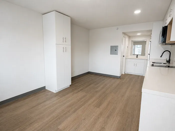 Bright and airy apartment featuring modern cabinetry, sleek countertops, and wood-style flooring.