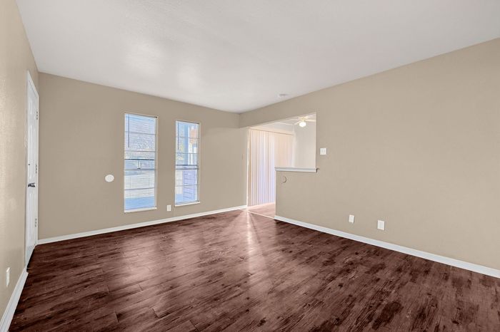 Bright and airy living space featuring elegant hardwood floors, large windows for natural light, and a smooth transition to the dining area.