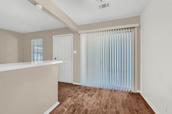 Inviting living space featuring sleek wooden floors, large window blinds, and an open layout for modern living.