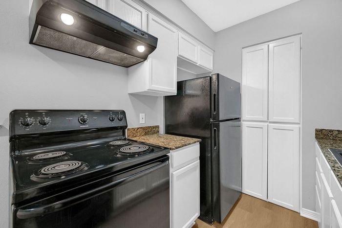 Chic modern kitchen with sleek black appliances, elegant granite countertops, and pristine white cabinetry.