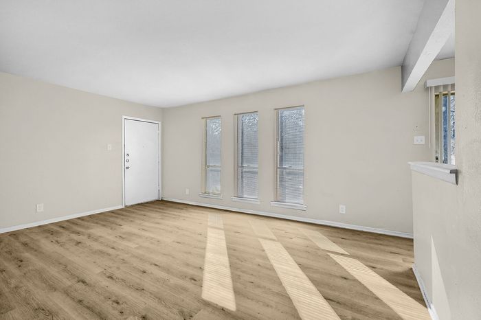 Bright living room with large windows, sleek wood flooring, and neutral walls offering a modern touch.