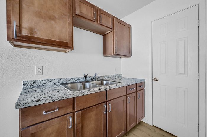 Sleek kitchen showcasing elegant wooden cabinetry and polished granite countertops with a modern dual-sink design.