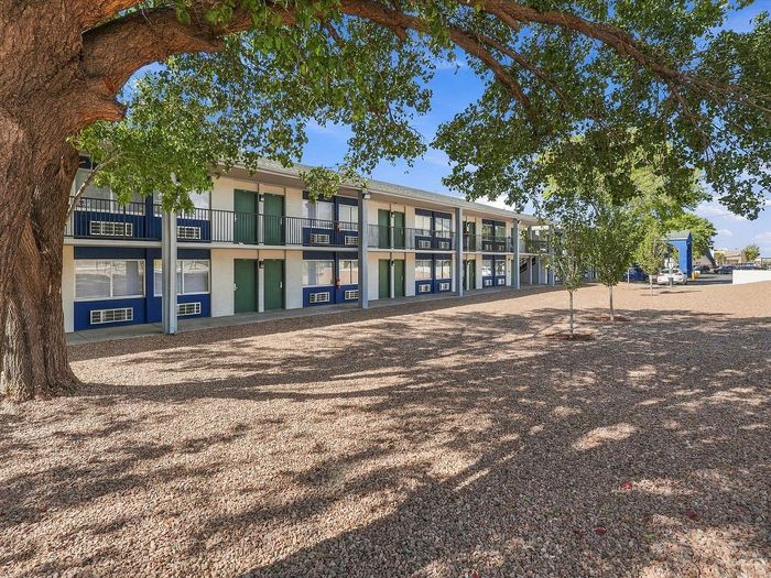 Courtyard with a large shade tree and gravel landscaping beside two-story buildings at Juniper Flats