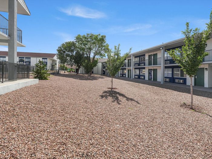 Desert-landscaped courtyard with young trees between two-story buildings at Juniper Flats in Albuquerque, NM
