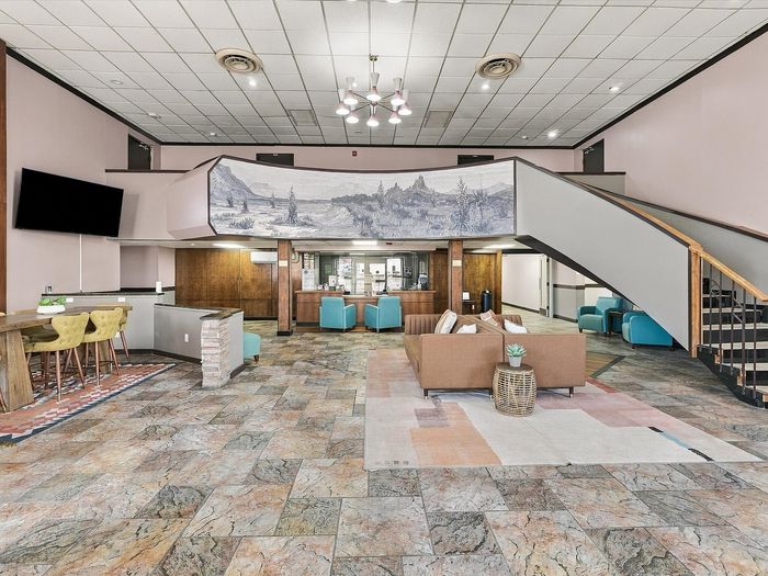 Two-story lobby with mountain mural, curved staircase, chandeliers and lounge seating at Juniper Flats