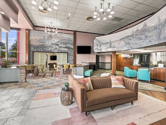 Lobby lounge with brown sofa, teal chairs and mountain mural at Juniper Flats apartments in Albuquerque