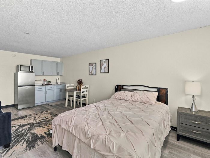 Studio apartment with bed, kitchenette, stainless refrigerator and small dining table at Juniper Flats