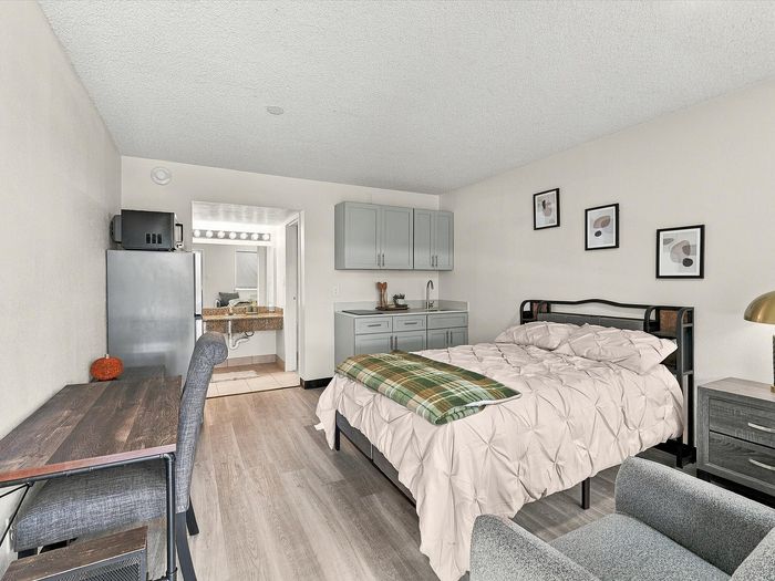 Studio apartment with bed, desk, kitchenette and vanity area at Juniper Flats in Albuquerque, NM