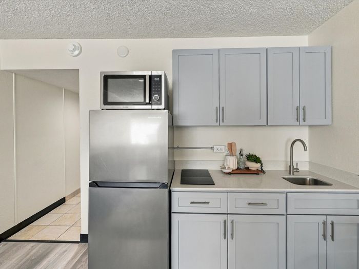 Kitchenette with gray cabinets, stainless refrigerator, microwave, cooktop and sink at Juniper Flats
