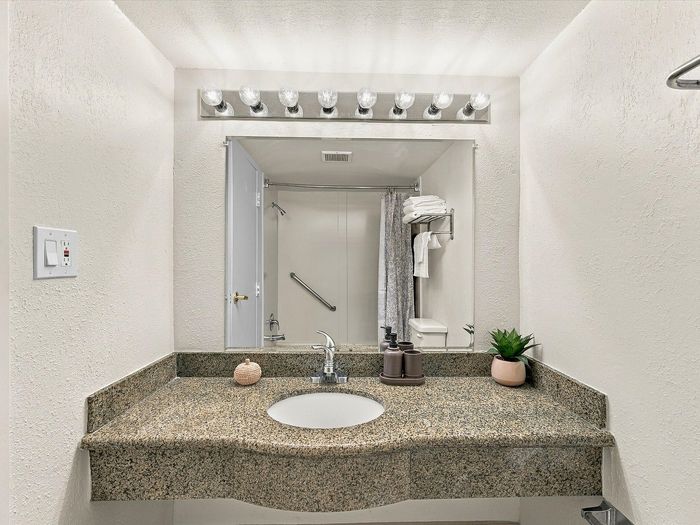 Bathroom vanity with granite-look counter, round sink, light bar and mirror at Juniper Flats