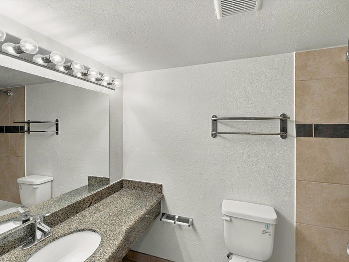 Bathroom with granite-look vanity, toilet, towel bar and tile accent wall at Juniper Flats