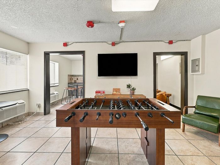 Resident game room with foosball table, wall TV and armchair at Juniper Flats in Albuquerque, NM