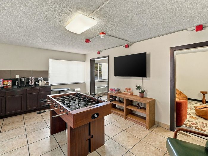 Game room with foosball, wall TV, console and coffee counter at Juniper Flats apartments