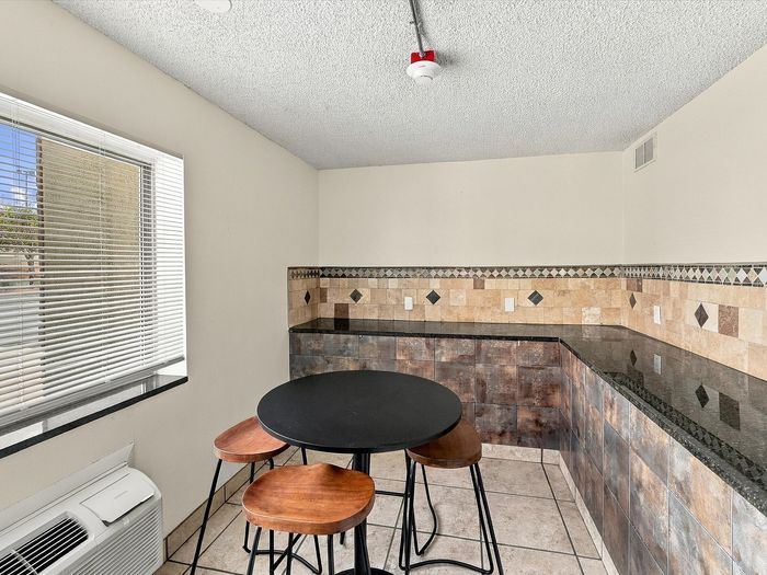 High-top table and stools beside a granite counter with tile backsplash at Juniper Flats
