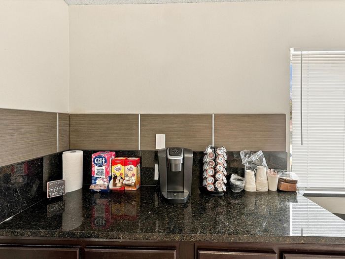 Resident coffee station with single-serve coffee maker, cups and creamer on a granite counter at Juniper Flats