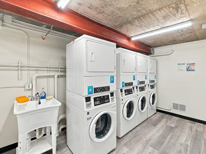 Laundry room with stacked washers and dryers and a utility sink at Juniper Flats apartments