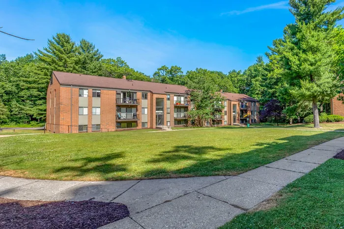 Charming apartment complex surrounded by lush greenery, featuring spacious balconies and a well-maintained lawn.