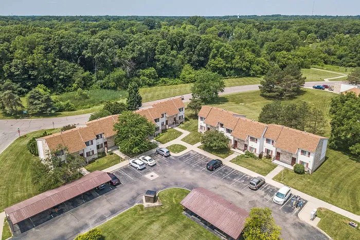 Charming suburban apartment complex with lush greenery, ample parking, and cozy buildings nestled in a tranquil, vibrant community setting.