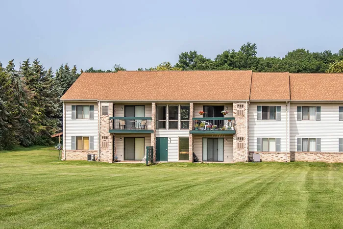 Charming apartment complex with private balconies, surrounded by lush greenery and peaceful landscaping.